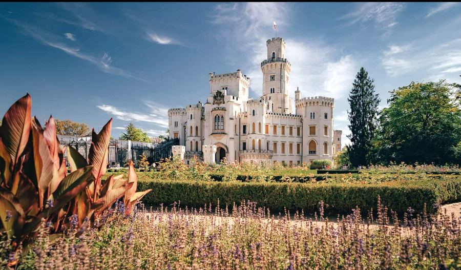 Bílý zámek Hluboká s věžemi za květinovou zahradou
