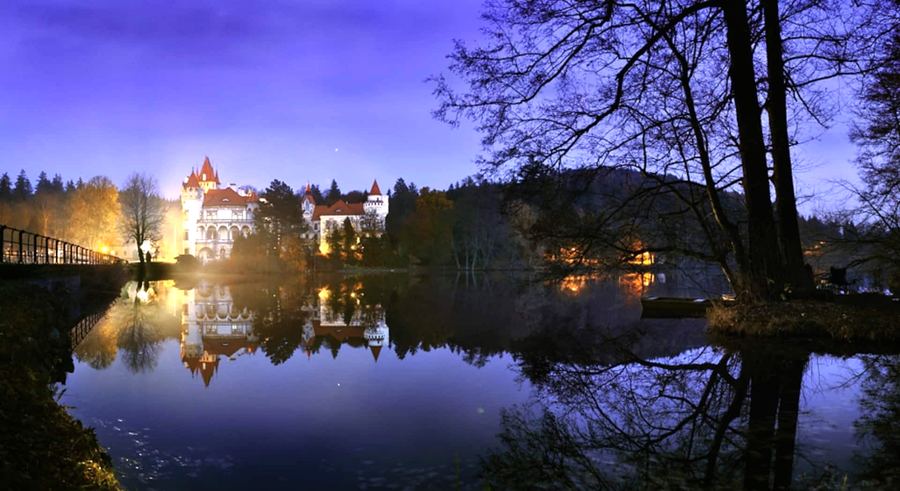Zámek Žinkovy osvětlený večer nad rybníkem